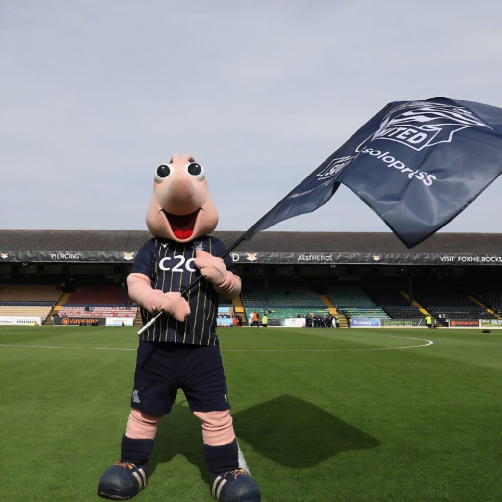 Sammy Running at mascot race. Sammy with a flag at Roots Hall